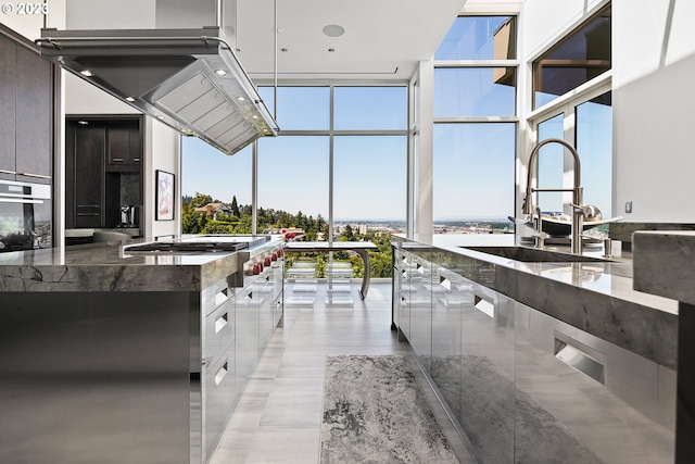 kitchen with dark stone counters, oven, hanging light fixtures, a wall of windows, and light tile floors