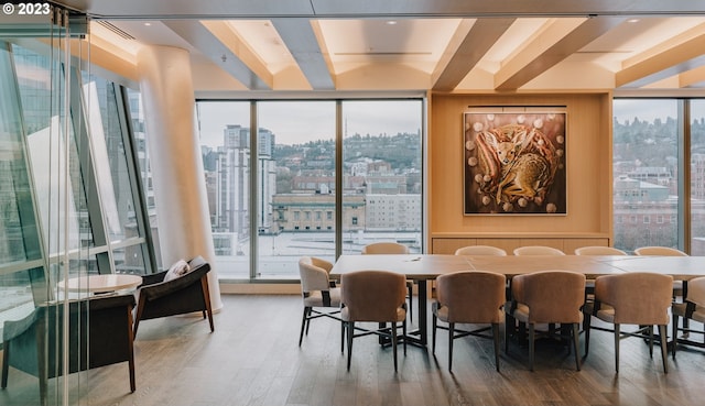 dining space with hardwood / wood-style floors, expansive windows, and a healthy amount of sunlight