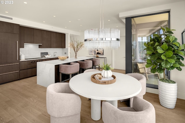 dining space with light hardwood / wood-style floors and an inviting chandelier