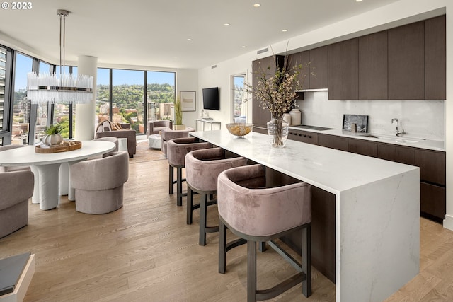 kitchen with a center island, light wood-type flooring, decorative light fixtures, and sink