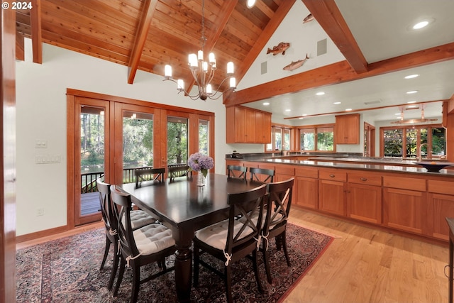 dining space featuring beamed ceiling, a healthy amount of sunlight, a chandelier, and light hardwood / wood-style flooring