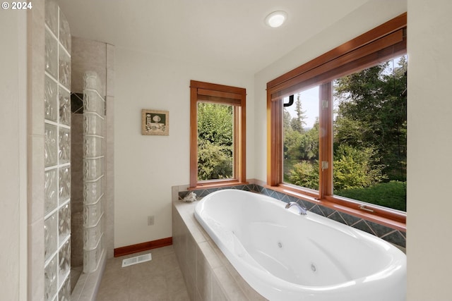 bathroom with a healthy amount of sunlight, tile patterned flooring, and tiled tub