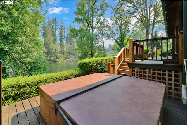 wooden terrace with a water view and a covered hot tub