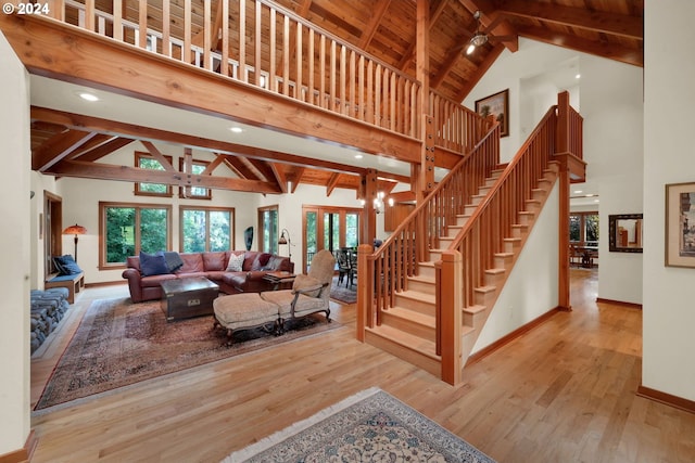 living room featuring beamed ceiling, high vaulted ceiling, light hardwood / wood-style flooring, and a notable chandelier