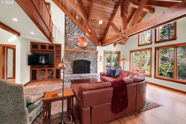 living room featuring wood ceiling, high vaulted ceiling, a fireplace, light hardwood / wood-style floors, and beamed ceiling