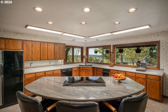 kitchen with a textured ceiling, sink, black appliances, tasteful backsplash, and a breakfast bar