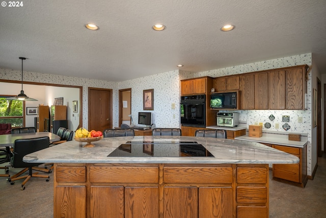 kitchen featuring a textured ceiling, black appliances, a center island, and decorative light fixtures