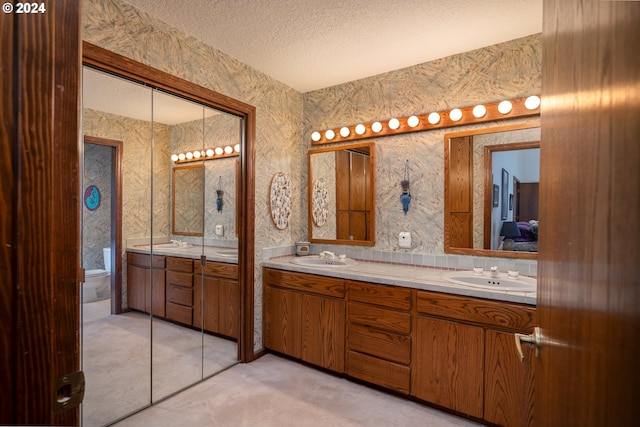 bathroom with vanity, toilet, and a textured ceiling