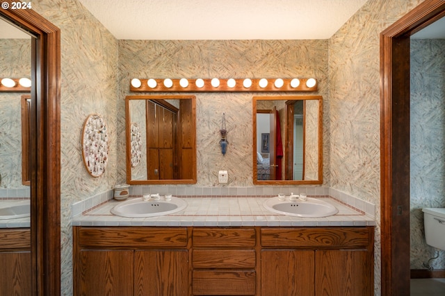 bathroom with toilet, a textured ceiling, and vanity