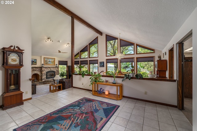 tiled living room with a textured ceiling, a healthy amount of sunlight, a stone fireplace, and high vaulted ceiling