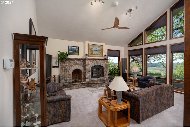 carpeted living room featuring a textured ceiling, high vaulted ceiling, ceiling fan, and a stone fireplace