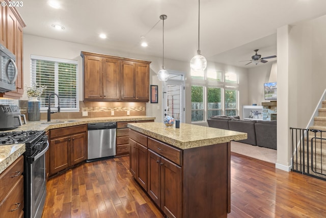 kitchen featuring appliances with stainless steel finishes, dark wood-type flooring, sink, pendant lighting, and a center island