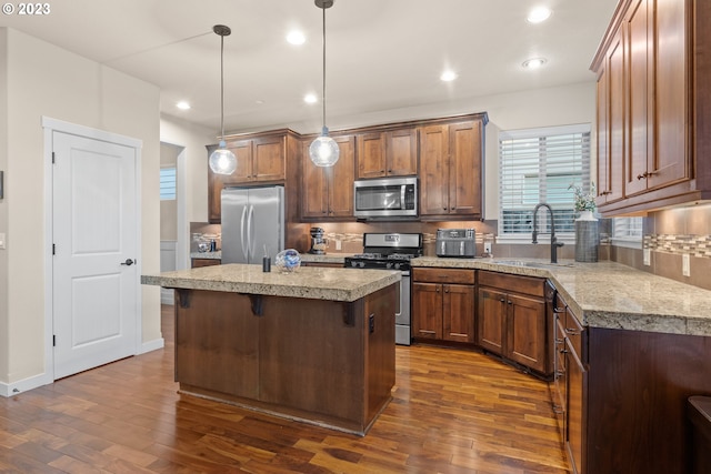 kitchen with sink, a center island, stainless steel appliances, dark hardwood / wood-style flooring, and decorative light fixtures