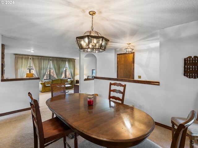 carpeted dining room featuring a textured ceiling and a notable chandelier