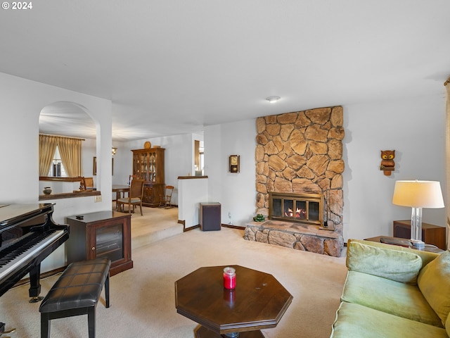 living room with a stone fireplace and light colored carpet