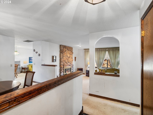 corridor featuring a textured ceiling and light carpet