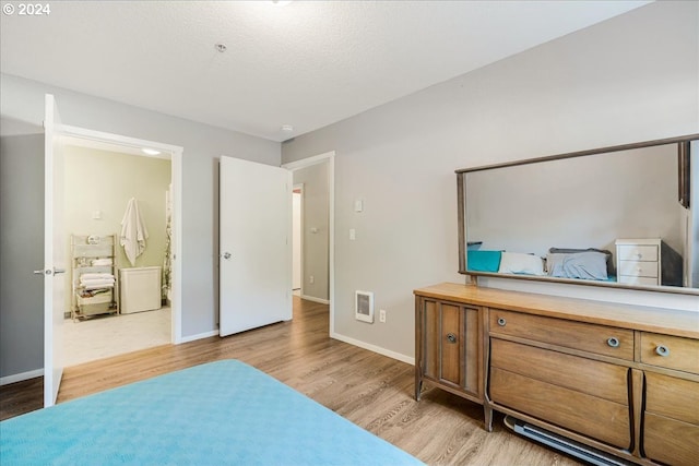 bedroom with ensuite bathroom and light hardwood / wood-style floors