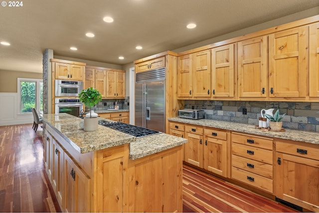 kitchen with backsplash, a center island, dark wood-type flooring, and appliances with stainless steel finishes