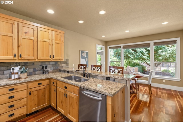 kitchen with kitchen peninsula, decorative backsplash, light stone countertops, dark wood-type flooring, and sink