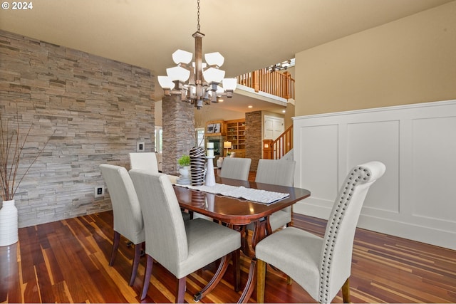 dining area with dark wood-type flooring and an inviting chandelier