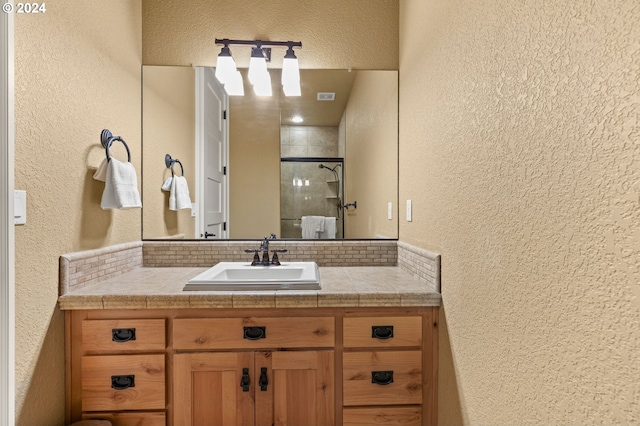 bathroom featuring decorative backsplash, a shower with door, and vanity