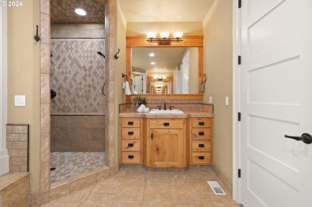 bathroom featuring tile patterned floors, vanity, a textured ceiling, and tiled shower