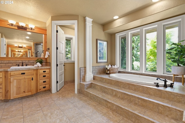 bathroom featuring tile patterned flooring, a textured ceiling, a wealth of natural light, and decorative columns