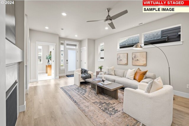 living room with ceiling fan, light wood-type flooring, and a fireplace