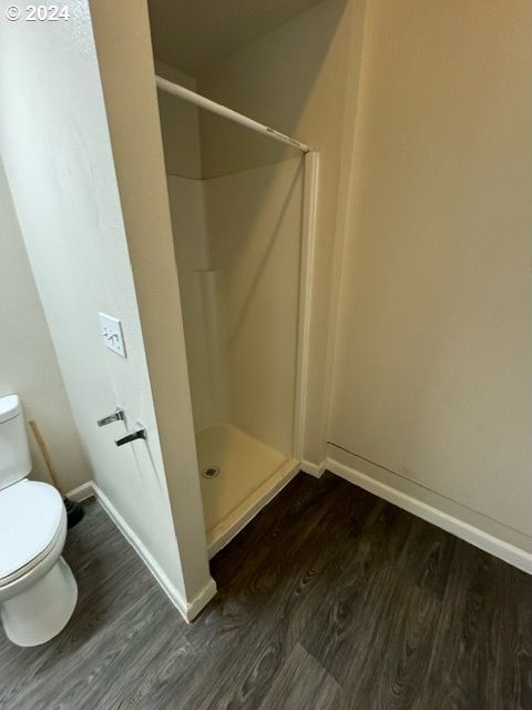 bathroom with toilet, a shower, and wood-type flooring