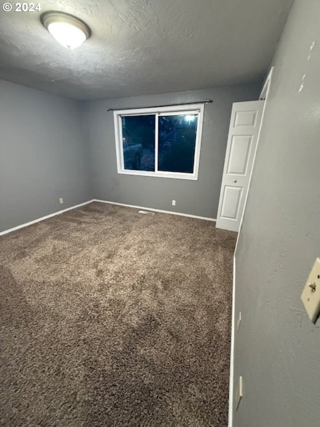 carpeted empty room featuring a textured ceiling