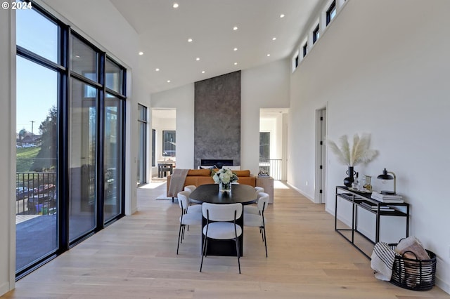 dining room featuring light hardwood / wood-style floors, a fireplace, and high vaulted ceiling