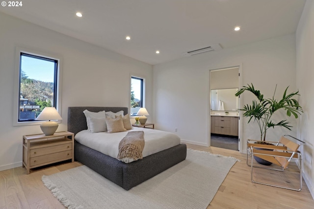 bedroom featuring light hardwood / wood-style floors, connected bathroom, and multiple windows