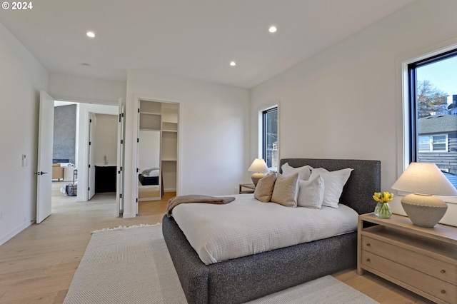 bedroom with a walk in closet, a closet, and light hardwood / wood-style floors