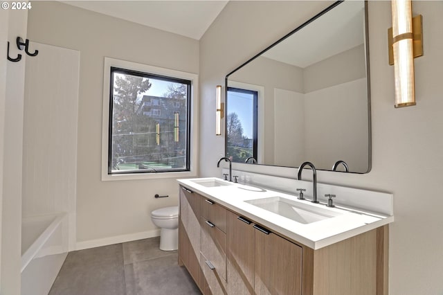 bathroom with tile patterned flooring, vanity, toilet, and a tub to relax in