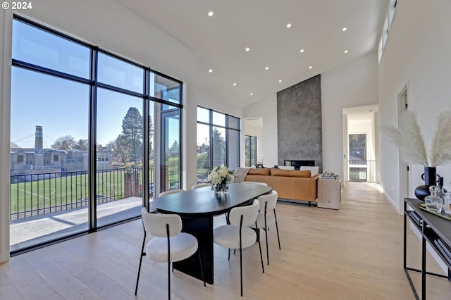 dining room featuring a large fireplace, a high ceiling, and light wood-type flooring