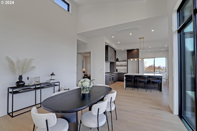 dining room with a towering ceiling and light hardwood / wood-style flooring