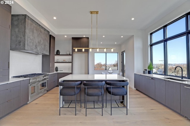 kitchen featuring light wood-type flooring, sink, range with two ovens, a kitchen island, and a breakfast bar area