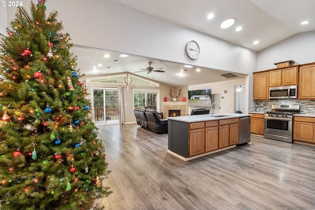 kitchen featuring a tile fireplace, sink, tasteful backsplash, a kitchen island with sink, and appliances with stainless steel finishes