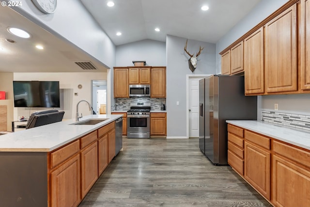 kitchen featuring a kitchen island with sink, dark wood-type flooring, sink, decorative backsplash, and stainless steel appliances