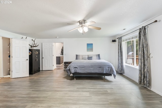 bedroom with ceiling fan, wood-type flooring, and a textured ceiling