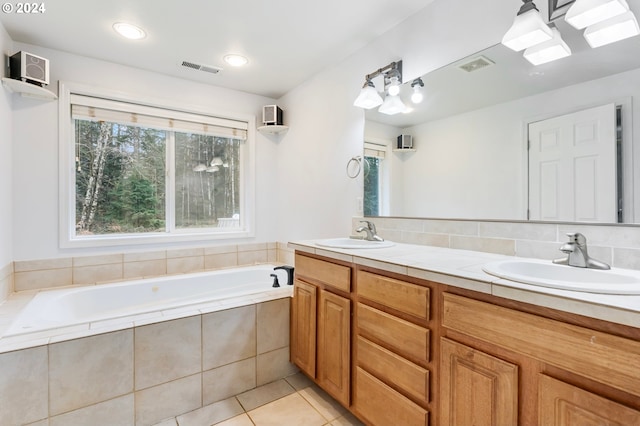 bathroom featuring tile patterned flooring, decorative backsplash, vanity, and tiled tub