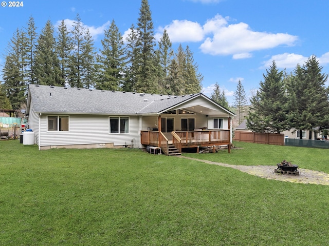 rear view of property featuring an outdoor fire pit, a lawn, and a wooden deck