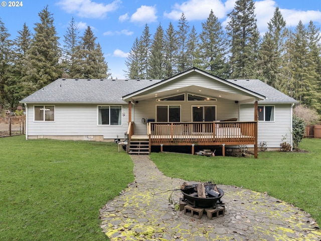 back of house with a deck, an outdoor fire pit, and a lawn