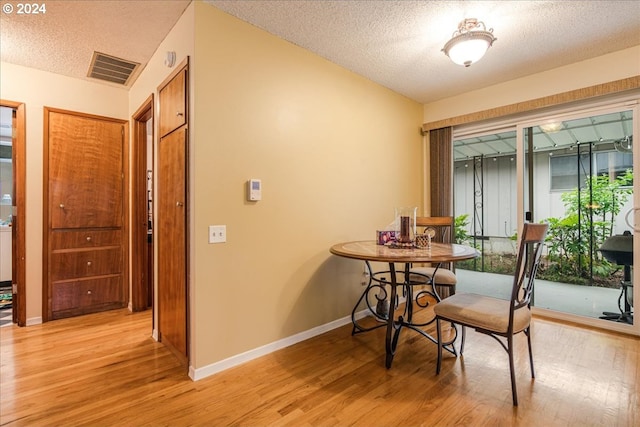 dining space featuring light hardwood / wood-style floors and a textured ceiling