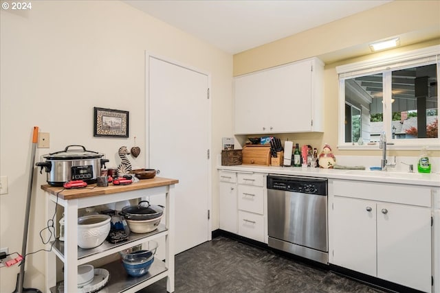 kitchen featuring sink, white cabinets, dark tile patterned floors, and stainless steel dishwasher