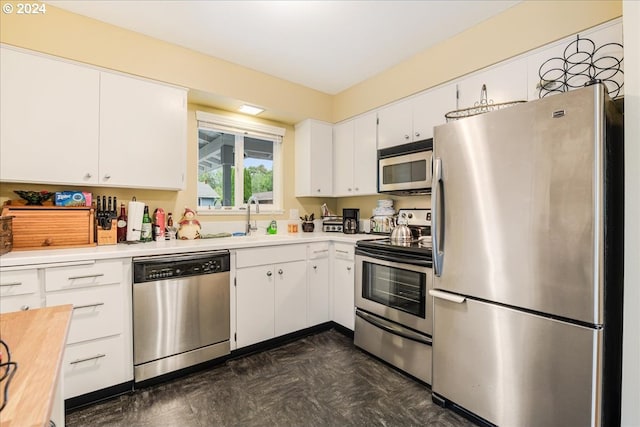 kitchen featuring dark tile patterned flooring, sink, stainless steel appliances, and white cabinets