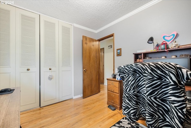 bedroom with light wood-type flooring, a textured ceiling, ornamental molding, and a closet