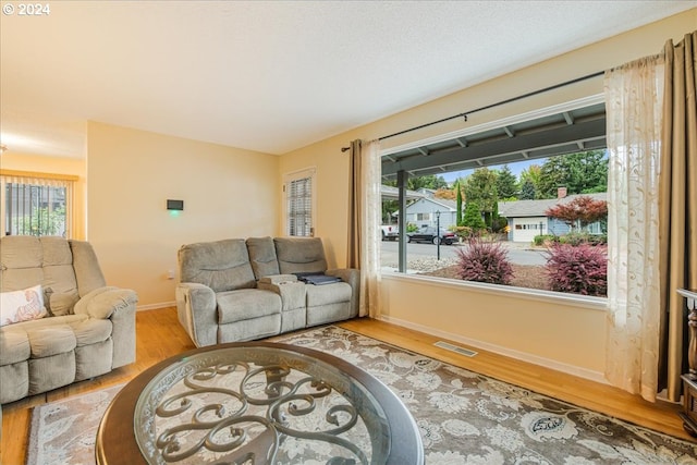 living room with baseboards, a wealth of natural light, visible vents, and light wood-style floors