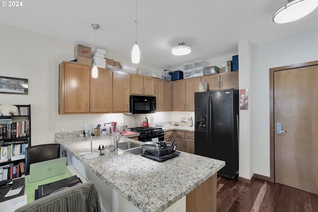 kitchen with a peninsula, dark wood-style flooring, hanging light fixtures, light stone countertops, and black appliances