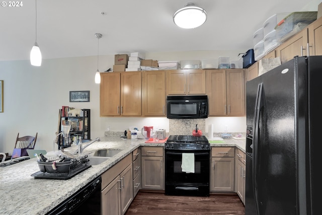 kitchen with a peninsula, a sink, black appliances, dark wood finished floors, and pendant lighting